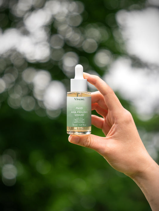 Hand holding a bottle of Vieve serum with a blurred green background